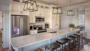 A modern kitchen with white cabinets, stainless steel appliances, and a central island with bar stools.