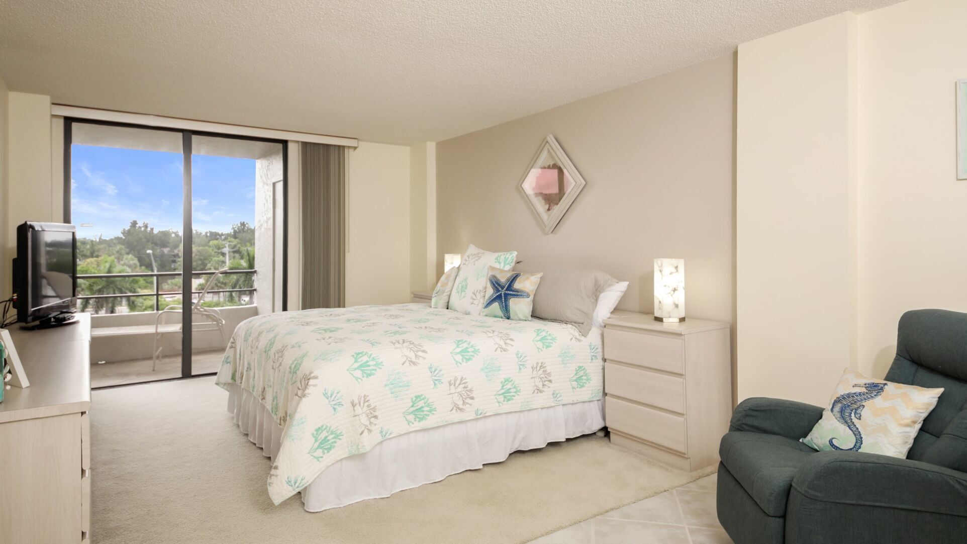 A hotel room with a bed, a TV, a balcony, and a chair.