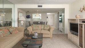 A living room with a beige sofa, a coffee table, and a TV on a cabinet. - Beautiful Apartment with first class amenities on The Anchorage, Siesta Key Apartment 1019 (Siesta Key)