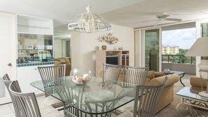 A modern dining area with a glass table and metal chairs, a ceiling fan, and a view of the city through large windows. - Beautiful Apartment with first class amenities on The Anchorage, Siesta Key Apartment 1019 (Siesta Key)
