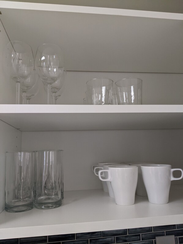 A kitchen shelf with various glassware and white ceramic cups. - Cute Edmonds Bowl Cottage (Edmonds)