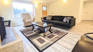 A living room with a sofa, armchair, coffee table, and a rug. - Cute Edmonds Bowl Cottage (Edmonds)