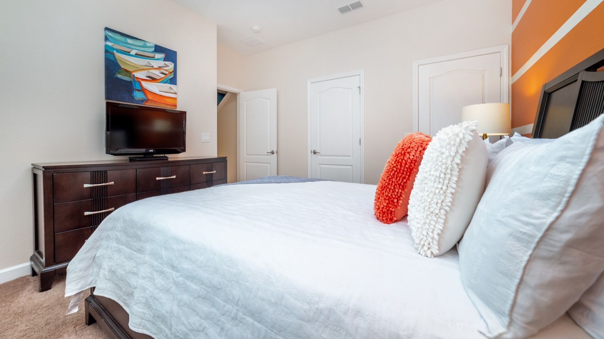 Une chambre à coucher avec un grand lit, une commode, un téléviseur et un tableau accroché au mur.