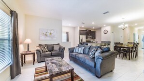 A modern living room with two sofas, a coffee table, and a dining area with a chandelier. - Beautiful 5 Star Townhome on Storey Lake Resort with Private Pool, Orlando Townhome 4807 (Orlando)