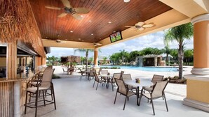 An outdoor dining area with tables and chairs, a pool, and a waterfall feature.