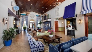 A spacious lobby with a high ceiling, patterned curtains, and a mix of seating areas including sofas and a table.