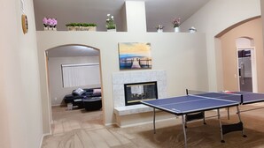 Ein Wohnzimmer mit Tischtennisplatte, Kamin und einer Couch.