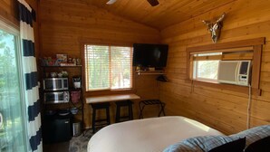 Una camera accogliente con un letto, una ventola a soffitto, una TV a parete e una finestra con tende.
