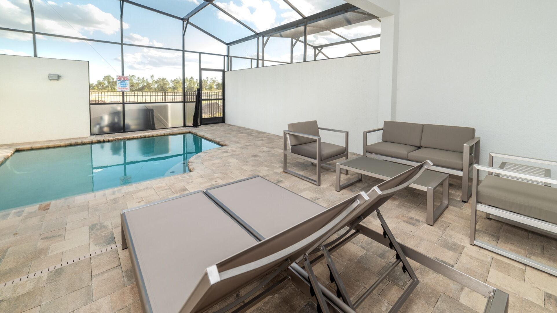 A pool area with a glass ceiling, outdoor seating, and a view of the sky.
