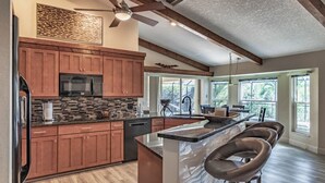 Una cocina moderna con armarios de madera, salpicadero de piedra y una isla grande con taburetes de bar.