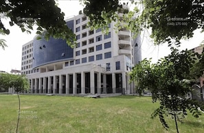 Stylish building with balconies and large windows, set amidst a beautifully landscaped area.