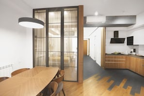 Enjoy meals in the dining area with a wooden table and chairs, surrounded by a large window and modern lighting.