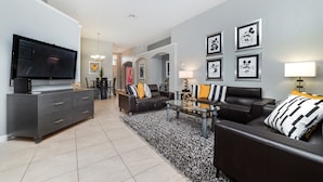 A modern living room with a flat-screen TV, a dark leather sofa, a coffee table, and a patterned rug. - Beautiful 5 Star Villa with Private Pool on the Prestigious Windsor Palms Resort, Orlando Villa 4886 (Orlando)