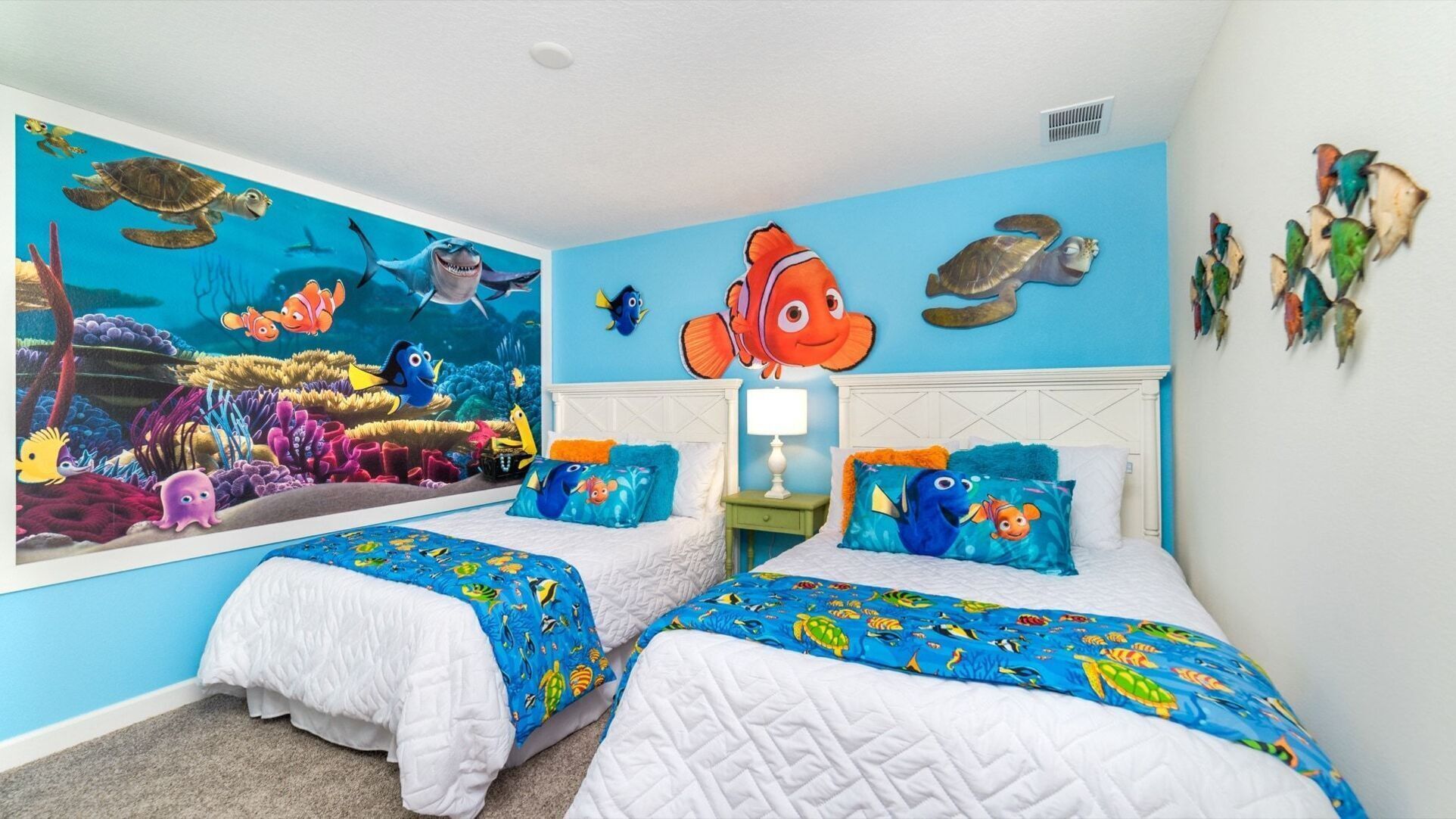 Une chambre avec deux lits, une fresque représentant des créatures marines et un mur bleu.