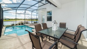 A covered outdoor area with a pool, dining table, and chairs.