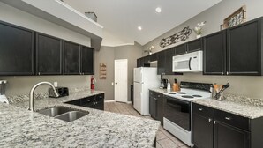 A kitchen with dark cabinets, granite countertops, a white refrigerator, a microwave, and a stove. - Exclusive 5 Star Villa with Private Pool on Windsor Palms Resort, Orlando Villa 4903 (Orlando)