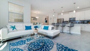 Ein modernes Wohnzimmer mit einem weißen Sofa, einem Glastisch und einem gemusterten Teppich.