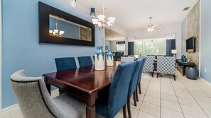 Un coin repas avec une table en bois foncé, des chaises à revêtement bleu et des vases décoratifs.