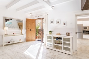 A bright, well-lit room with a wooden door, a white console table, a mirror, and a cabinet with shelves. - Holiday Home ‘Es Raco’ with Mountain View, Jacuzzi, Wi-Fi, Air Conditioning & Terraces (Costitx)