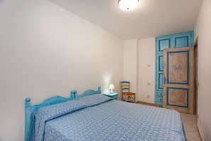 A bedroom with a bed, a nightstand, a chair, and a wardrobe.