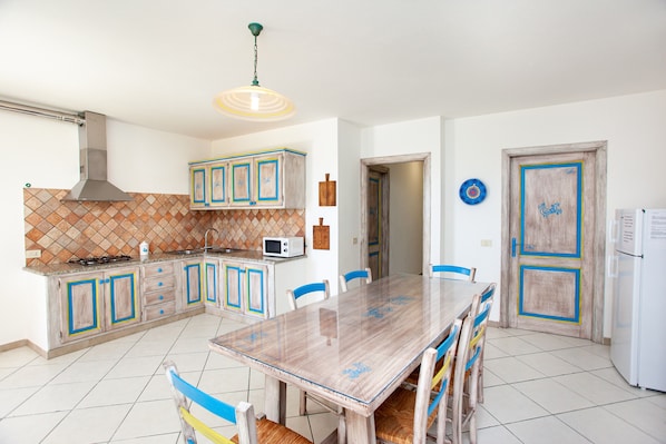 A kitchen with a tiled backsplash, a stove, a microwave, and a dining table with chairs.