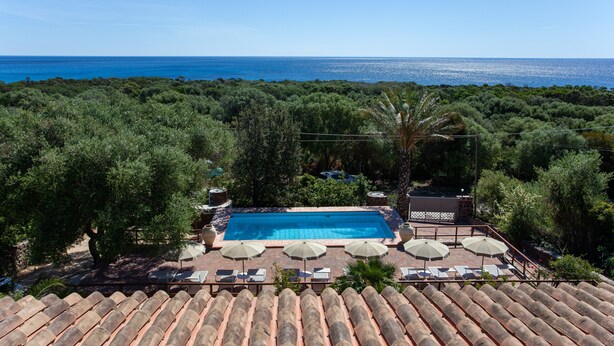 A rooftop pool with a view of the sea, surrounded by trees and umbrellas. - Holiday Apartment 'Pavoncella' with Wi-Fi, Garden & Shared Pool (Orosei)