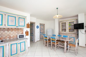 A kitchen with a dining area, a microwave, cabinets, and a television.