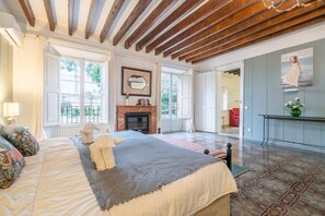 A spacious bedroom with a large bed, a fireplace, and a view of the outdoors.