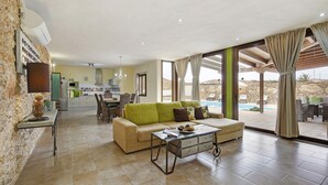 A spacious living area with a sofa, coffee table, and a view of a pool.