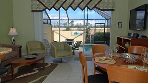 A living room with a pool view, furnished with sofas, chairs, and a dining table. - Exclusive Townhome with Large Private Pool on Windsor Hills Resort, Orlando Townhome 4923 (Orlando)