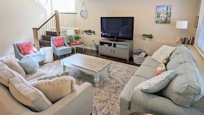 A living room with a staircase, a flat-screen TV, and a bookshelf. - Spacious Westside  Wine Trail Retreat ★★★★★ (West Kelowna)