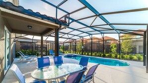 A covered outdoor area with a pool, lounge chairs, and a table. - Luxury Villa with Private Pool on Solterra Resort, Orlando Villa 4946 (Orlando)