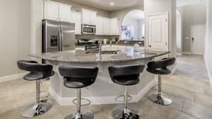 A modern kitchen with a central island, stainless steel appliances, and bar stools. - Luxury Villa with Private Pool on Solterra Resort, Orlando Villa 4946 (Orlando)