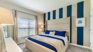 Ein Schlafzimmer mit einem großen Bett, zwei Nachttischen, einer Lampe und einem Fenster mit Jalousien.