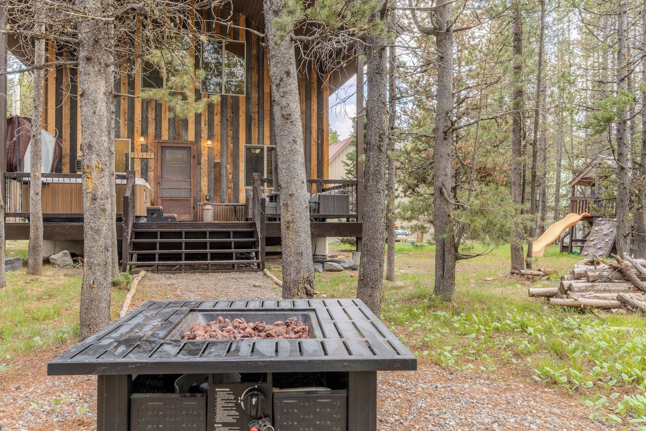 Une cabane rustique avec une façade en bois, une terrasse et un foyer au premier plan.