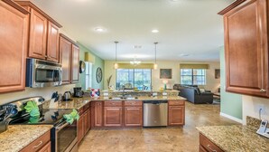 A spacious kitchen with granite countertops, stainless steel appliances, and wooden cabinets. - Rent Your Own Exclusive Villa with Large Private Pool on Champions Gate Resort, Orlando Villa 5002 (Orlando)