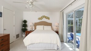 Relax in a spacious room with a large bed, two bedside tables, and a ceiling fan. Enjoy the view from the large window and step out onto the balcony with comfortable seating.