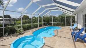 Relax by the pool surrounded by a brick patio and lounge chairs.