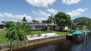 A residential area with a house, a covered outdoor area, and a dock by a body of water.