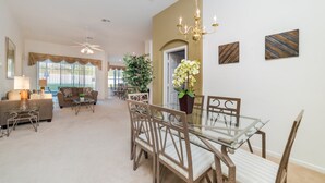 A spacious living room with a dining area, large windows, and a chandelier.