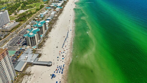 Un hotel costero con varias construcciones, una playa y una vista despejada del océano.