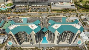 Un hotel de gran altura con varios balcones, una piscina central y ubicación frente a la playa.