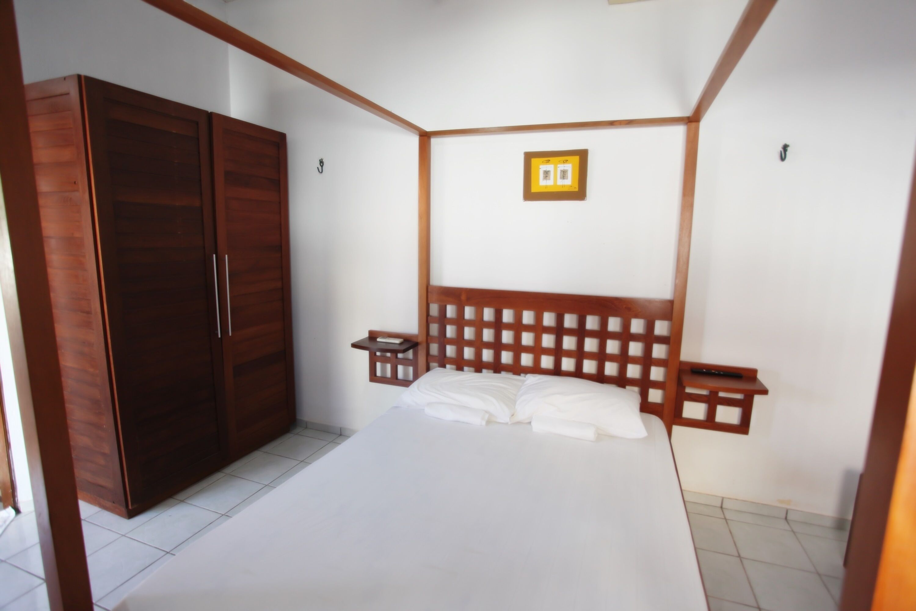 Une chambre à coucher avec un grand lit, une armoire en bois et une tête de lit ornée d’un motif quadrillé.