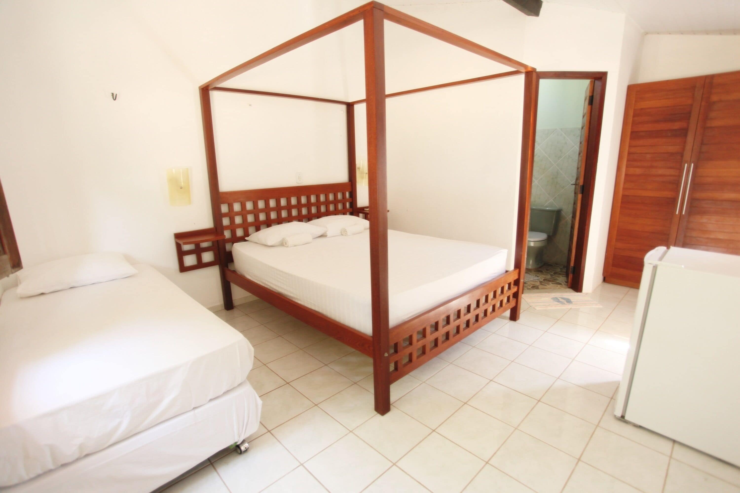 A bedroom with a four-poster bed, a single bed, and a wardrobe.