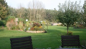 A garden with a bench and a table, surrounded by various plants and trees.