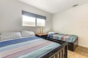 A bedroom with two beds, a window, and a nightstand.