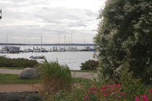 Ein Yachthafen mit vertäuten Booten, eine Rasenfläche mit Steinen und ein Baum mit weißen Blüten.