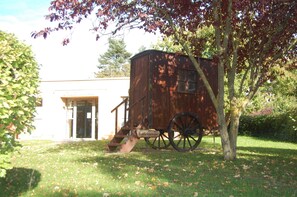 A wooden carriage parked in front of a building with a glass door and a staircase leading up to it.