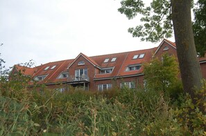 Ein großes Backsteingebäude mit vielen Fenstern und einem roten Ziegeldach.