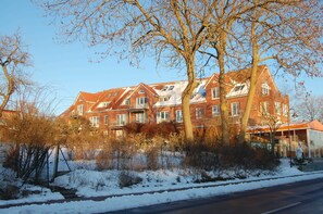 A large, multi-story brick building with a symmetrical facade, multiple windows, and a prominent entrance with a glass door.